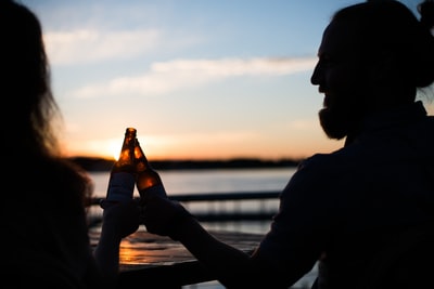 男人和女人拿着啤酒瓶的剪影摄影
